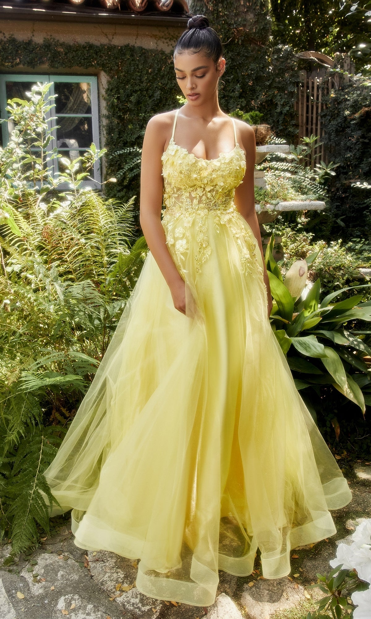 Outdoors in a garden, a woman wears the Flower-Embellished Long Tulle Prom Ball Gown A1142, featuring thin straps and 3D floral details.